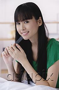 AsiaPix - Young woman filing nails, looking at camera