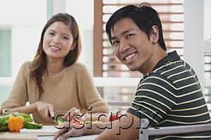 AsiaPix - Couple looking at camera, woman chopping vegetables, focus on the man in foreground