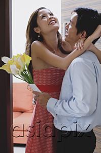 AsiaPix - Couple at doorway, man holding flowers, woman embracing him