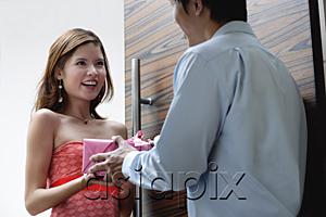 AsiaPix - Couple standing at doorway, man giving woman a present