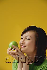 AsiaPix - Young Woman holding apple, eyes closed