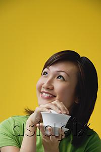 AsiaPix - Young woman holding teacup, looking away