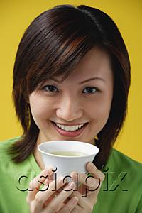 AsiaPix - Young woman holding Chinese tea cup, smiling at camera