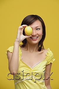 AsiaPix - Young woman holding lemon over her eye