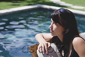 AsiaPix - Young woman leaning on deck chair by swimming pool