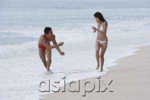 AsiaPix - Couple running along beach, man splashing woman with water