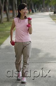AsiaPix - Mature woman using dumbbells, walking along path