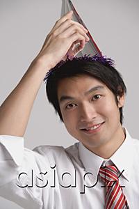 AsiaPix - Businessman wearing party hat, looking at camera