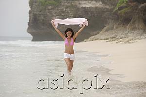 AsiaPix - Woman in pink bikini, running along beach, holding scarf in air