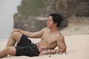 AsiaPix - Man lying on beach, looking away