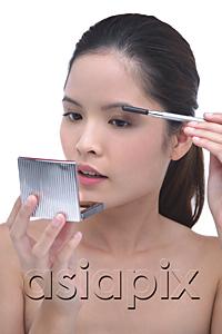 AsiaPix - Young woman brushing eyebrows, looking at compact mirror