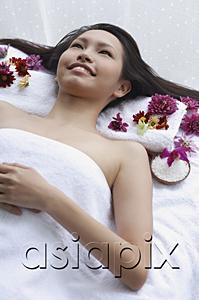 AsiaPix - Young woman lying down on massage table, looking up