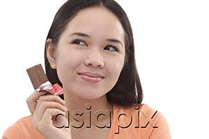 AsiaPix - Young woman with a bar of chocolate, looking away