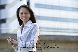 AsiaPix - Female executive smiling at camera, hands clasped