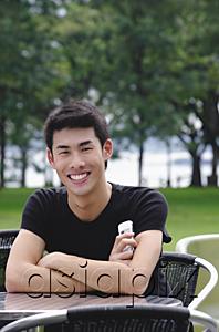 AsiaPix - Man sitting at outdoor cafe, arms crossed, smiling
