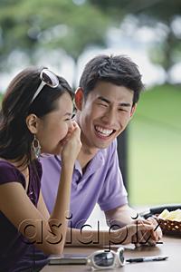 AsiaPix - Couple sitting at cafe, young woman with hand over mouth, smiling