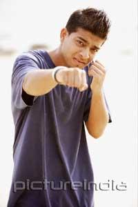 PictureIndia - Young man throwing a punch, looking at camera