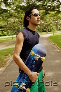PictureIndia - Man wearing sunglasses, holding skateboard