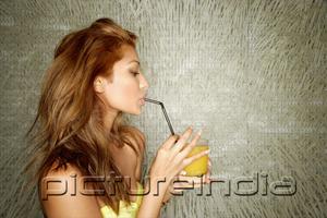 PictureIndia - Young woman sipping drink with straw