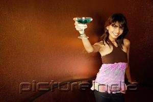 PictureIndia - Young woman holding drink up towards camera