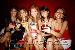 PictureIndia - Women sitting side by side, smiling at camera, holding drinks