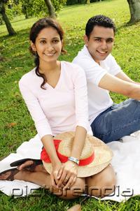PictureIndia - Couple in park, sitting on grass, looking at camera