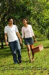 PictureIndia - Couple walking in park, woman carrying picnic basket