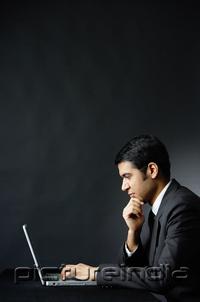 PictureIndia - Businessman in front of laptop, hand on chin
