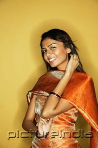 PictureIndia - Woman in Indian clothing, smiling at camera, hand on neck