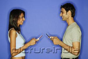 PictureIndia - Couple face to face, holding mobile phones