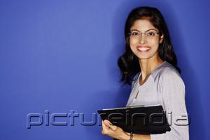 PictureIndia - Woman looking at camera, carrying clipboard