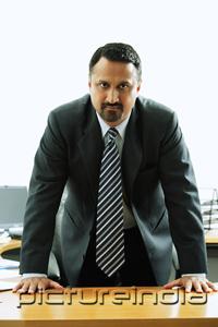 PictureIndia - Businessman standing at desk, looking at camera