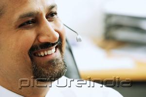 PictureIndia - Man using headset, smiling