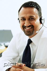 PictureIndia - Man using headset, smiling at camera