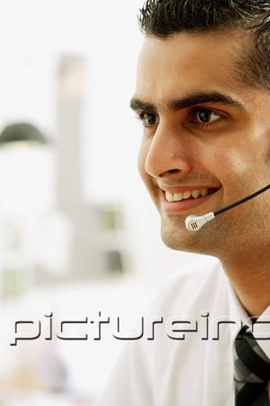 PictureIndia - Executive using headset, smiling, head shot