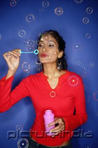 PictureIndia - Woman blowing bubbles from bubble wand