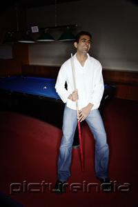 PictureIndia - Young man leaning against pool table, smiling