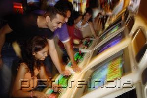 PictureIndia - Young adults in video arcade, playing games