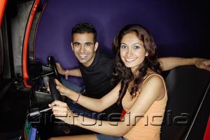 PictureIndia - Couple in a video game arcade, playing games, smiling at camera
