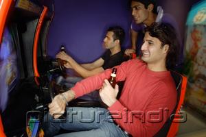 PictureIndia - Young men in amusement arcade playing video games