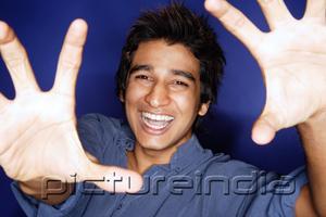 PictureIndia - Man with palm of hands showing towards camera, smiling
