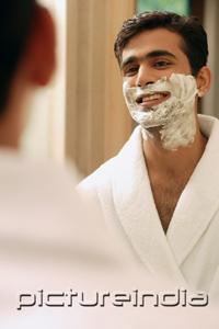 PictureIndia - Man with shaving cream on face, looking in mirror