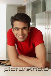 PictureIndia - Man leaning on kitchen counter, looking at camera