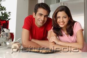 PictureIndia - Couple leaning on kitchen counter, looking at camera
