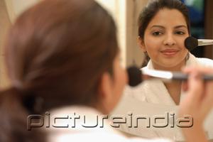 PictureIndia - Woman applying blusher, looking in mirror