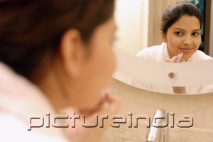 PictureIndia - Woman applying lipstick, looking in mirror