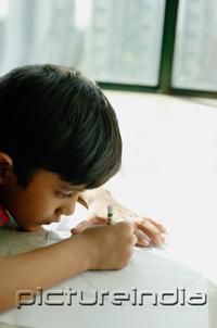 PictureIndia - Boy lying on floor, drawing with crayons