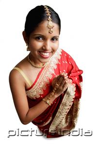 PictureIndia - Woman in sari, standing with hands together, smiling up at camera