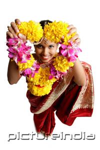 PictureIndia - Woman in sari, holding flower garland up towards camera