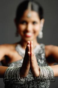 PictureIndia - Woman in gray sari smiling at camera, hands together, selective focus